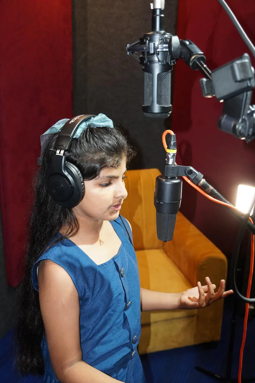 Young student singing into a studio microphone with headphones